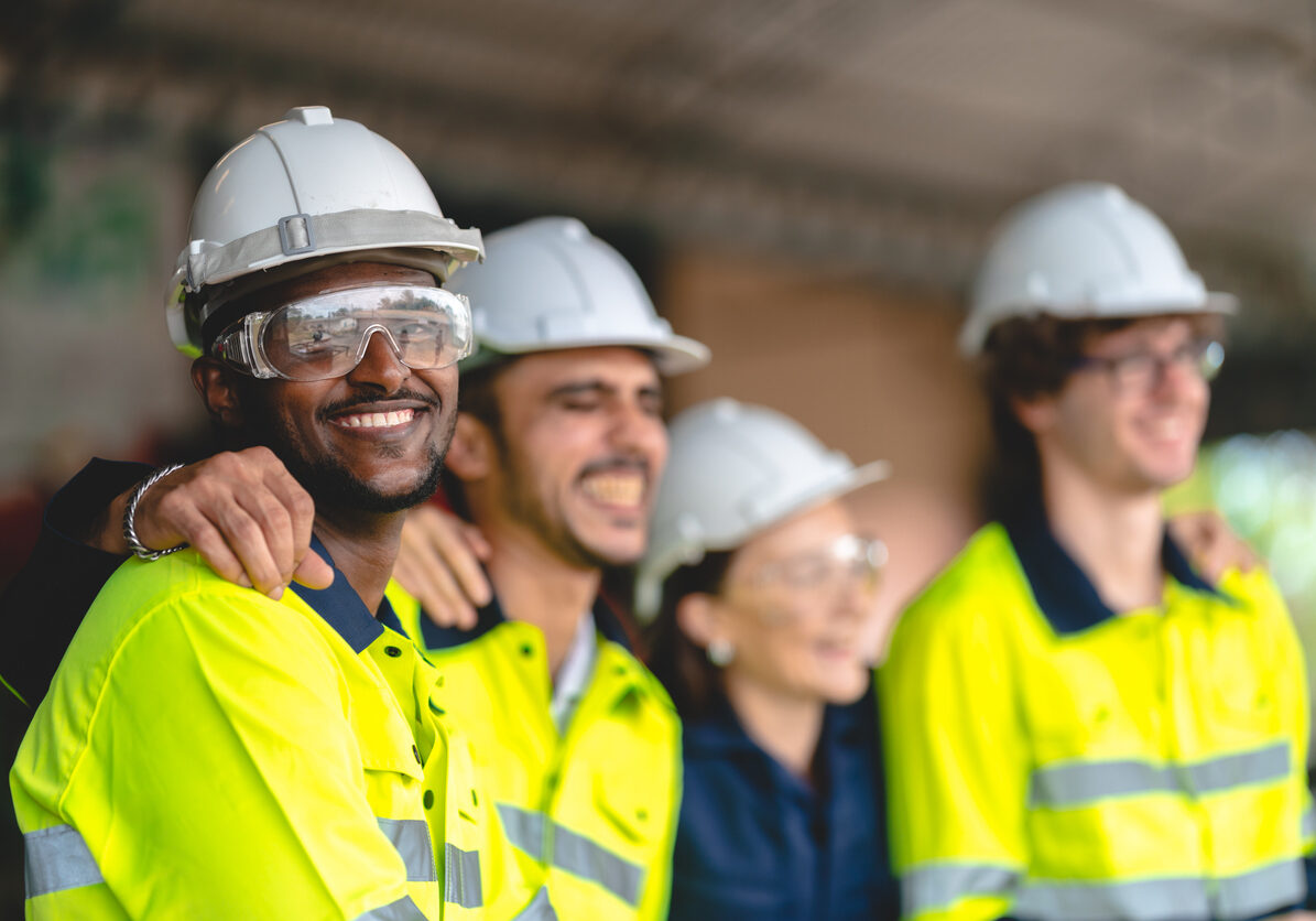 Group of construction workers smiling in safety gear and hard hats